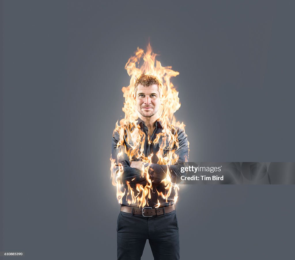 Man confidently poses with arms folded whilst on fire