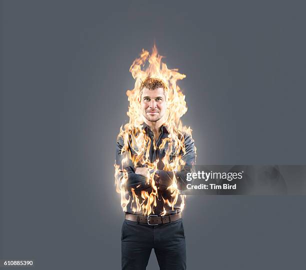 man confidently poses with arms folded whilst on fire - burning stock pictures, royalty-free photos & images