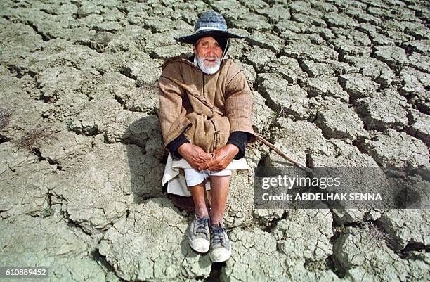 Un berger est assis, le 30 mars 2000, sur le sol asséché d'un barrage d'eau situé dans la région de Tanger, au nord du Maroc, suite à la sécheresse...