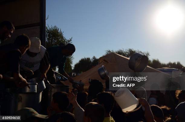 Syrians refugees gather to receive food, provided by relief organizations, at the Nour camp north of Aleppo on the Syrian-Turkish border on September...