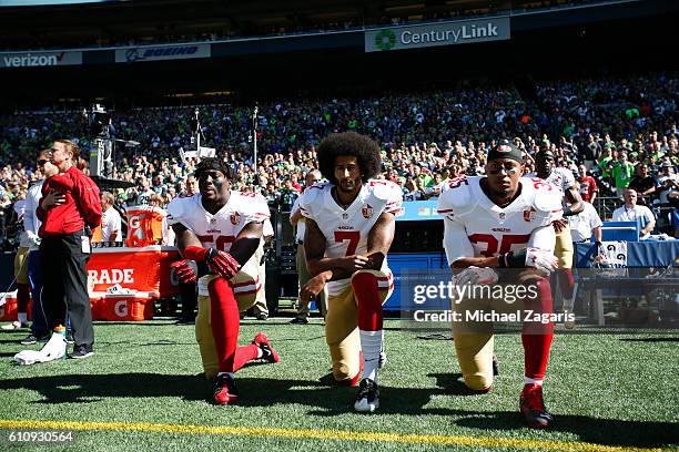 Eli Harold, Colin Kaepernick and Eric Reid of the San Francisco 49ers kneel on the sideline during the anthem prior to the game against the Seattle...