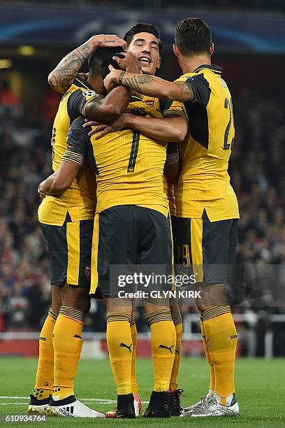 Arsenal's English midfielder Theo Walcott celebrates with teammates after scoring the opening goal of the UEFA Champions League Group A football...