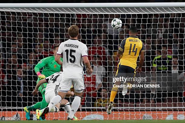 Arsenal's English midfielder Theo Walcott heads the opening goal past Basel's Czech goalkeeper Tomas Vaclik during the UEFA Champions League Group A...
