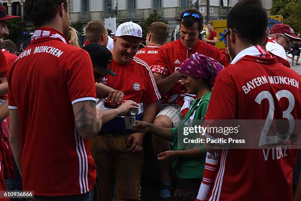 Bayern supporter pours beer into the glass of a beggar in Madrid. Several Bayern Munich supporters have been accused of humiliating beggars at Plaza...