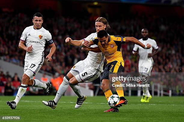 Alexis Sanchez of Arsenal shoots at goal under pressure from Michael Lang of Basel during the UEFA Champions League group A match between Arsenal FC...