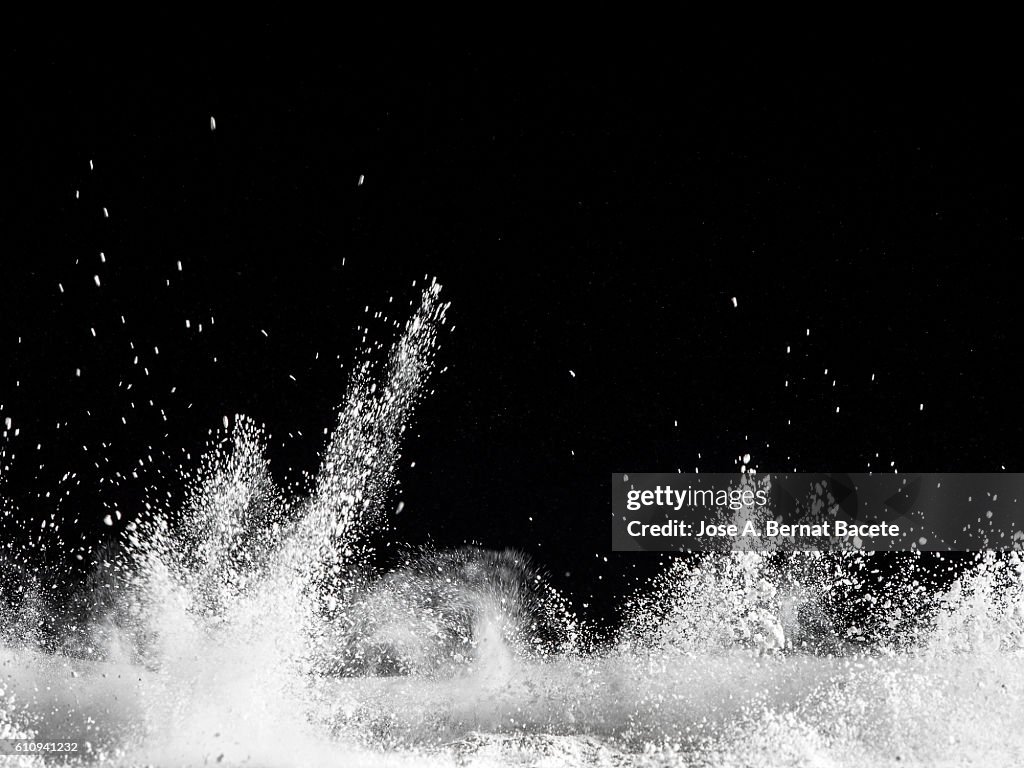 Explosion particles of white powder on a black background