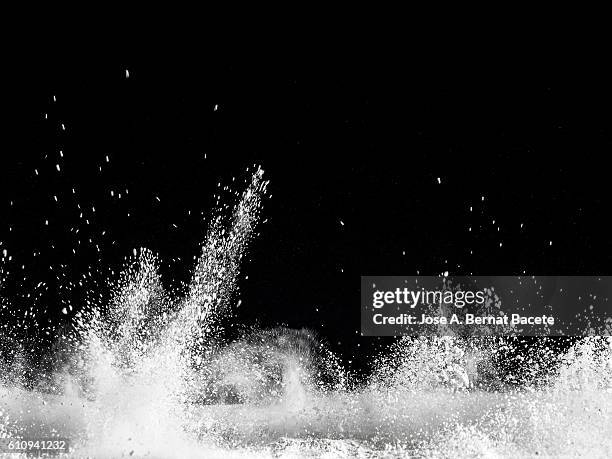 explosion particles of white powder on a black background - black powder stock-fotos und bilder