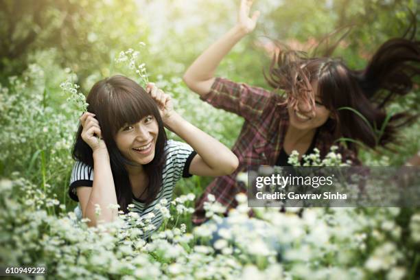 portrait of beautiful asian girl in meadow holding wild flowers. - girl long hair stock pictures, royalty-free photos & images