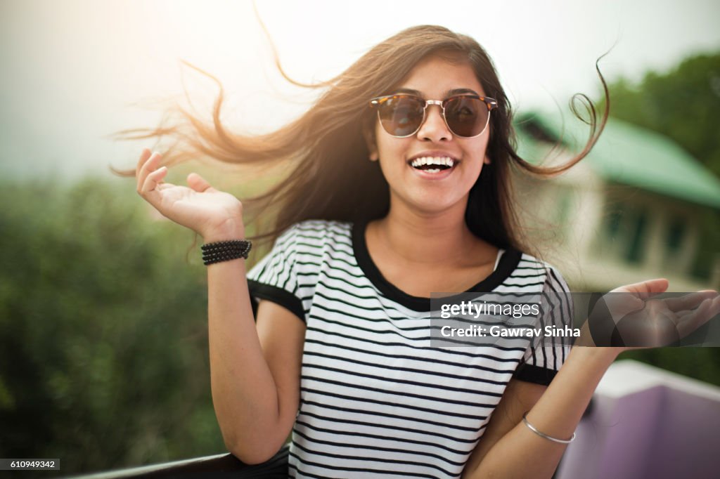 Beautiful girl wearing sunglasses enjoying fresh air in balcony.