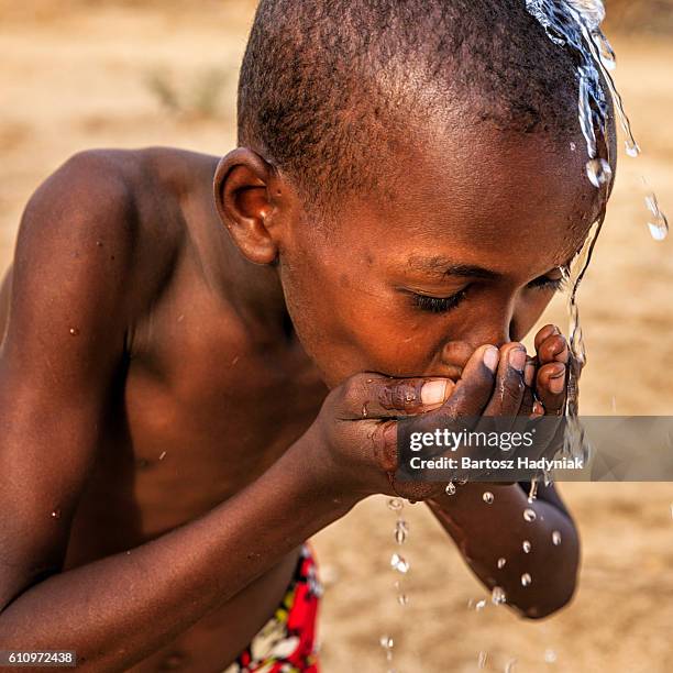 african young boy drinking fresh water on savanna, east africa - thirsty stock pictures, royalty-free photos & images