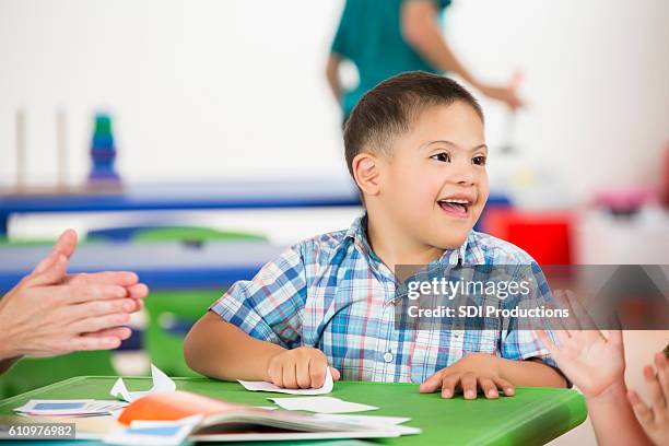 chico juguetón con el syndrom de down se divierte con su compañero de clase - downsyndrom fotografías e imágenes de stock