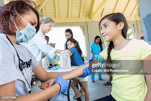 doctor examines preteen patient at free clinic - community health stock pictures, royalty-free photos & images