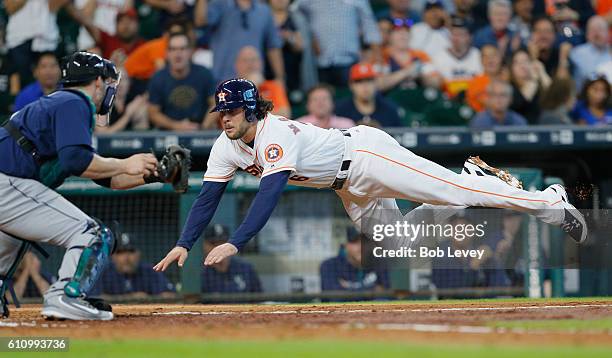 Jake Marisnick of the Houston Astros scores in the fifth inning as he avoids the tag by catcher Mike Zunino of the Seattle Mariners at Minute Maid...