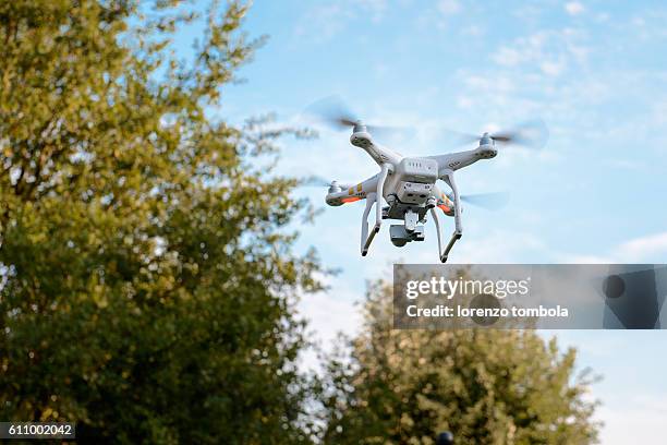 quadcopter drone with camera flying among the trees - クワッドコプター ストックフォトと画像