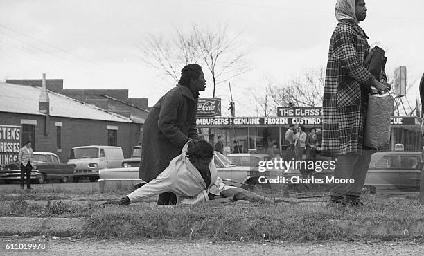 Unidentified women stand over the unconscious body of Civil Rights activist Amelia Boynton at the base of the Edmund Pettus Bridge during the first...