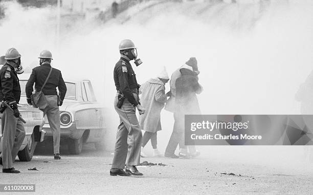 View of police officers in a gas masks and Civil Rights marchers in a cloud of tear gas at the base of the Edmund Pettus Bridge during the first...