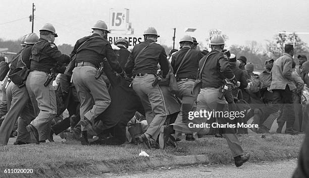 Armed police officers in gas masks charge at demonstrators at the base of the Edmund Pettus Bridge during the first Selma to Montgomery March, Selma,...