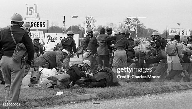 Armed police officers in gas masks charge at demonstrators at the base of the Edmund Pettus Bridge during the first Selma to Montgomery March, Selma,...