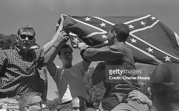 View of segregationist University of Mississippi students as they hold up a Confederate flag during an ongoing riot, Oxford, Mississippi, September...