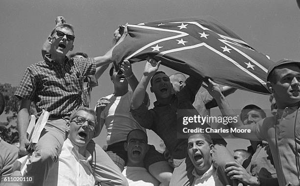 View of segregationist University of Mississippi students as they hold up a Confederate flag during an ongoing riot, Oxford, Mississippi, September...