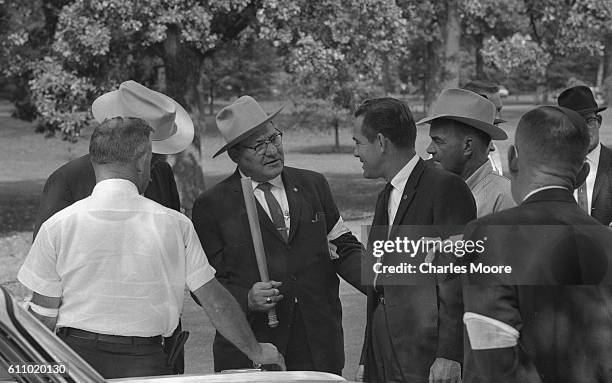 View of sheriff's department reserve deputies , one with a billy club, talk beside a car in a park, Oxford, Mississippi, late September 1962. They...