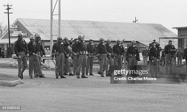 View of police officers in gas masks lined up across Broad Street at the base of the Edmund Pettus Bridge to stop the first Selma to Montgomery...