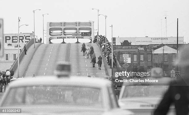 View of Civil Rights marchers as they walk back over the Edmund Pettus Bridge after being stopped by police violence during the first Selma to...