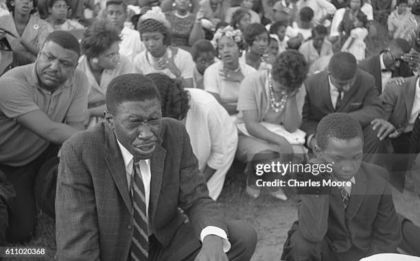 During a Civil Rights demonstration, a large group of well-dressed demonstrators kneel on a sidewalk and pray, Birmingham, Alabama, 1963.