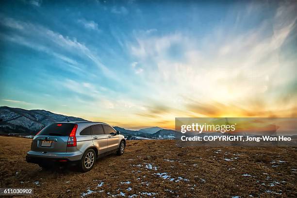 a car leaving into the sunset - cielo romantico foto e immagini stock