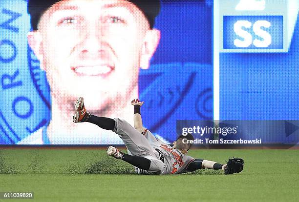 Nolan Reimold of the Baltimore Orioles makes a sliding catch to take a potential hit away from Troy Tulowitzki of the Toronto Blue Jays and turning a...