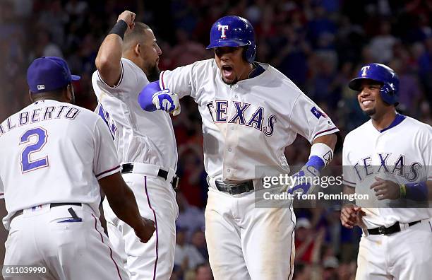 Carlos Gomez of the Texas Rangers celebrates with Rougned Odor of the Texas Rangers and Hanser Alberto of the Texas Rangers after hitting a three run...