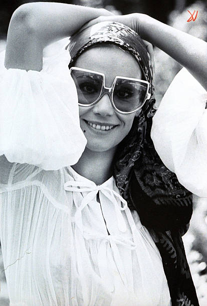 Claudine Auger, French actress, wearing sunglasses by Piave, a scarf on her head and a white blouse with full sleeves.