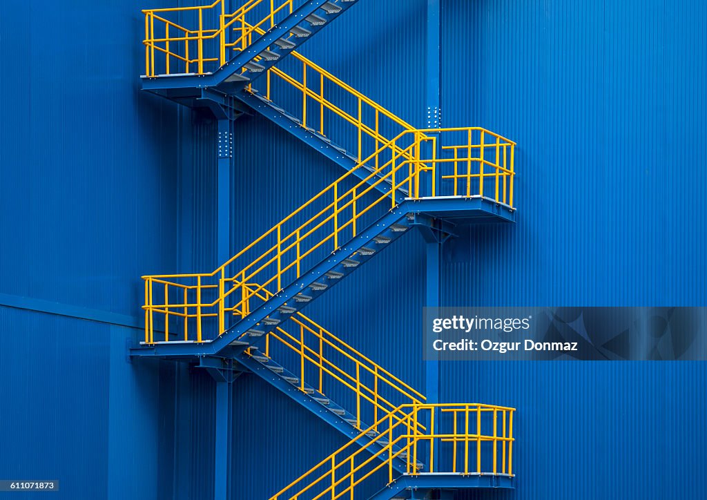 Yellow metal staircase against a blue wal