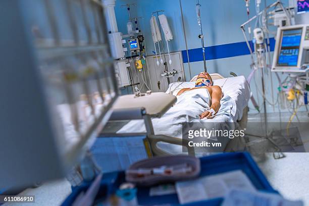young man lying in a hospital bed strapped to machines - intensive care unit stock pictures, royalty-free photos & images