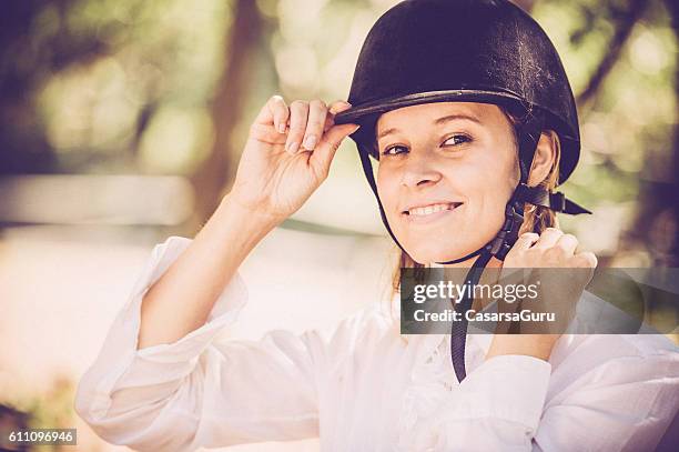 junge frau, die für ein reiten gelesen wird - equestrian helmet stock-fotos und bilder