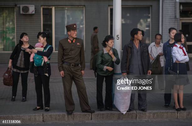 In this picture taken on September 29, 2016 commuters wait for a bus during the morning rush hour in Pyongyang.
