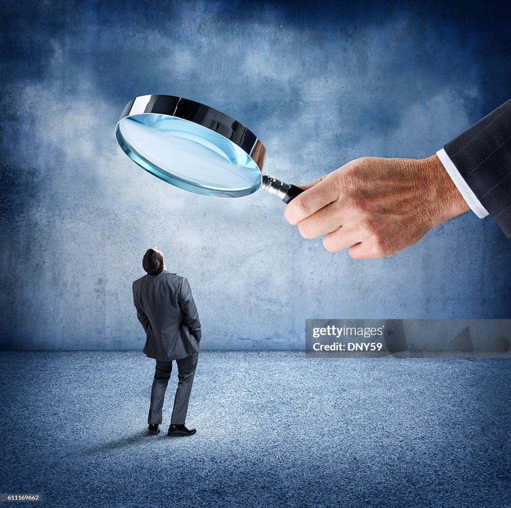 Businessman Looks Up At Businessman Holding Large Magnifying Glass