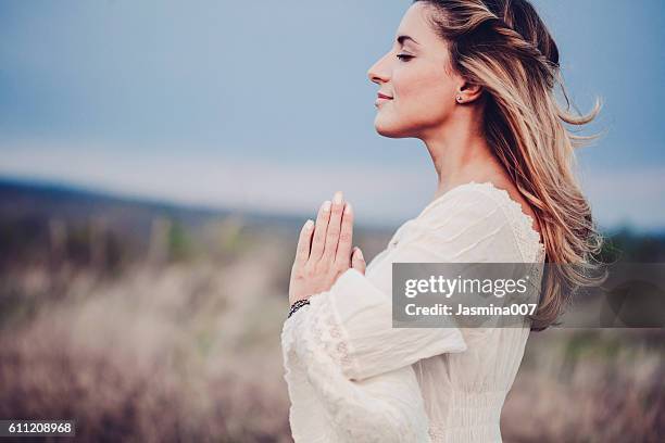 schöne frau auf einer wiese - women prayer stock-fotos und bilder