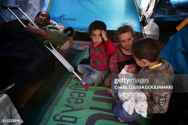 Syrian children hold their four-week old brother inside their tent at the municipality-run Souda camp on the Greek island of Chios on September 29,...