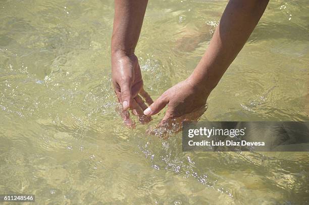 woman at the beach sand water washing hands - washing hands close up stock pictures, royalty-free photos & images