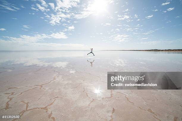 ferne frau springt auf salzsee - australia summer reflection stock-fotos und bilder