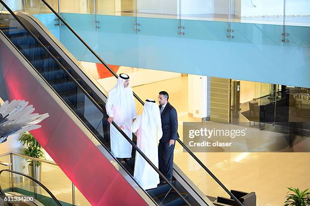 three arab business men entering building - escalator stock pictures, royalty-free photos & images