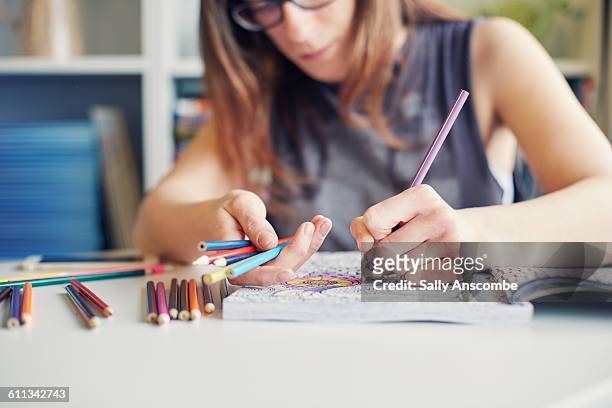 young woman colouring in an adult colouring book - livro de colorir imagens e fotografias de stock