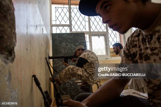 Fighter loyal to Libya's Government of National Accord , fires his weapon from a former school on the western frontline towards Islamic State group...