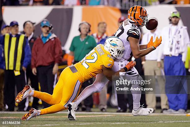 Uzomah of the Cincinnati Bengals is unable to hang on to the pass while being hit by Spencer Paysinger of the Miami Dolphins during the second...