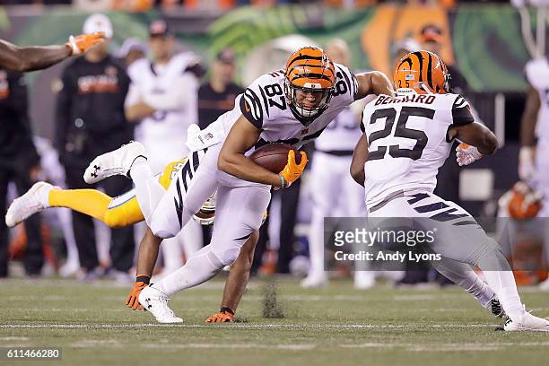 Uzomah of the Cincinnati Bengals gets tripped up by Spencer Paysinger of the Miami Dolphins during the second quarter at Paul Brown Stadium on...