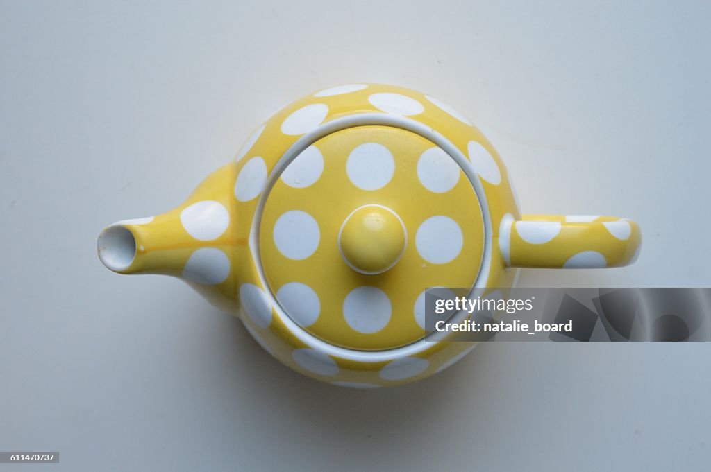 Directly Above View Of Yellow Polka Dot Tea Pot On White Background