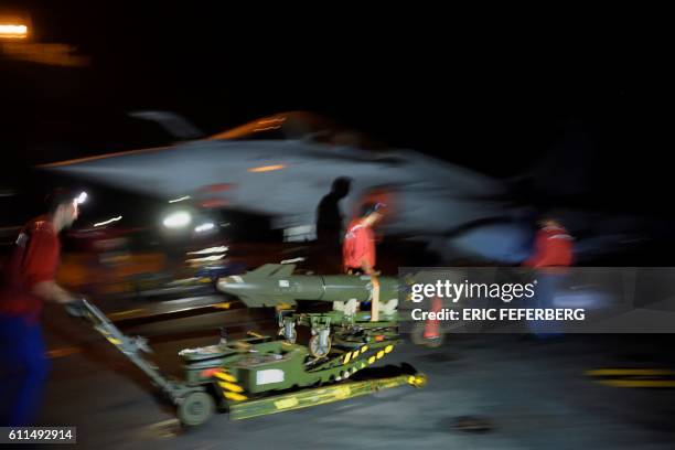 French navy technicians load a Dassault Rafale fighter jet with a guided laser missile as the plane is made ready for an upcoming sortie on the...