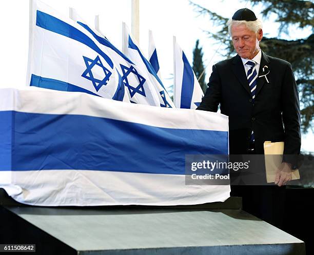 Former US President Bill Clinton touches the coffin of Shimon Peres after delivering his eulogy during the funeral at Mount Herzl Cemetery on...