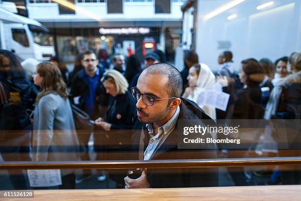 Customer looks through the window as he queues to enter the Dominique Ansel Bakery, on its opening day in London, U.K., on Friday, Sept. 30, 2016....